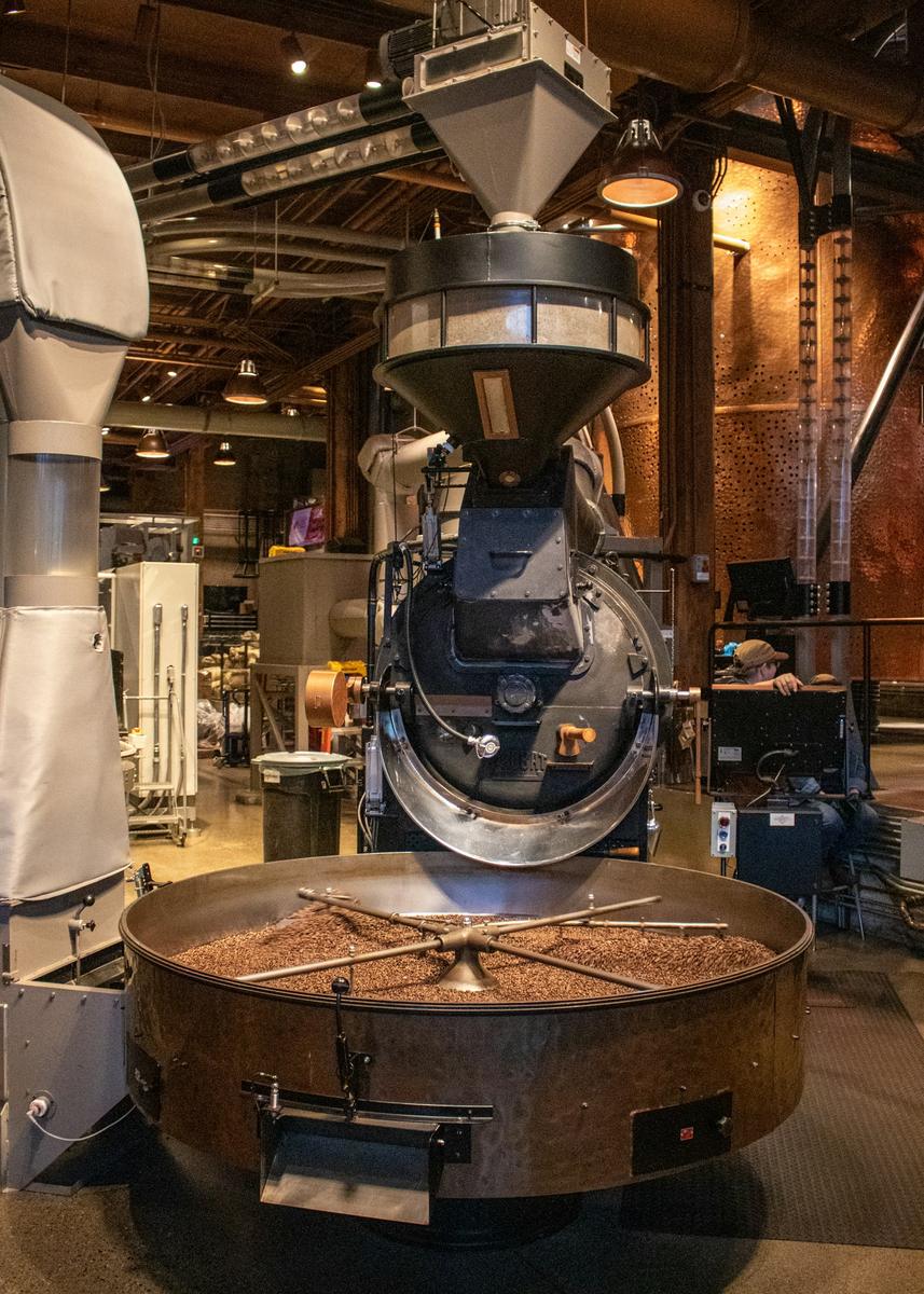 Industrial coffee roaster with a cooling tray of roasted beans
